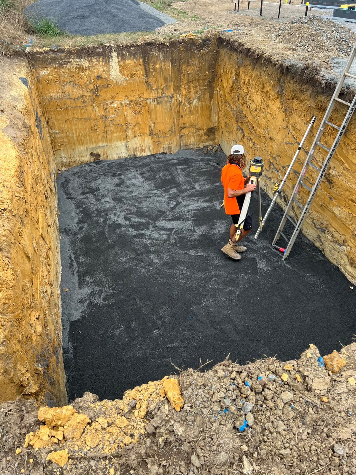 Operator levelling the base of a deep pool excavation