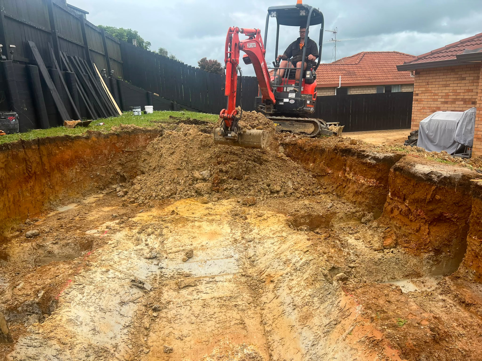Kubota excavator digging a swimming pool in a back yard